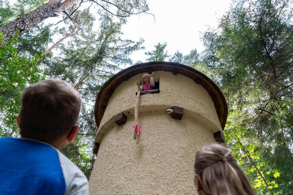 Zwei Kinder schauen zu Rapunzel im Freizeitpark Märchenwald hoch