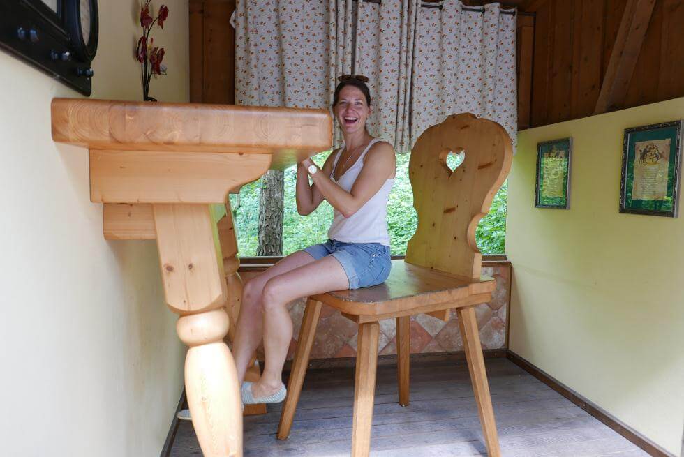 Besucherin auf einem riesigen Stuhl an einem riesigen Tisch